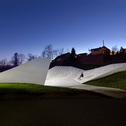 Sloping concrete volumes enclose social hub and chapel in a Slovenian village