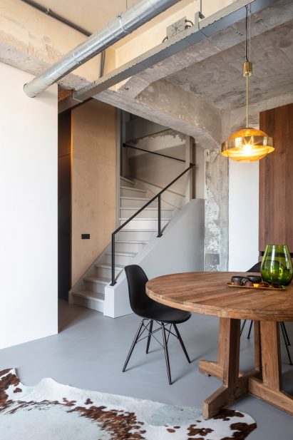 Wooden table and chair and exposed services inside the De Lakfabriek by Wenink Holtkamp Architecten