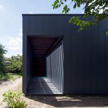 Monolithic black house conceals internal courtyard containing a single tree