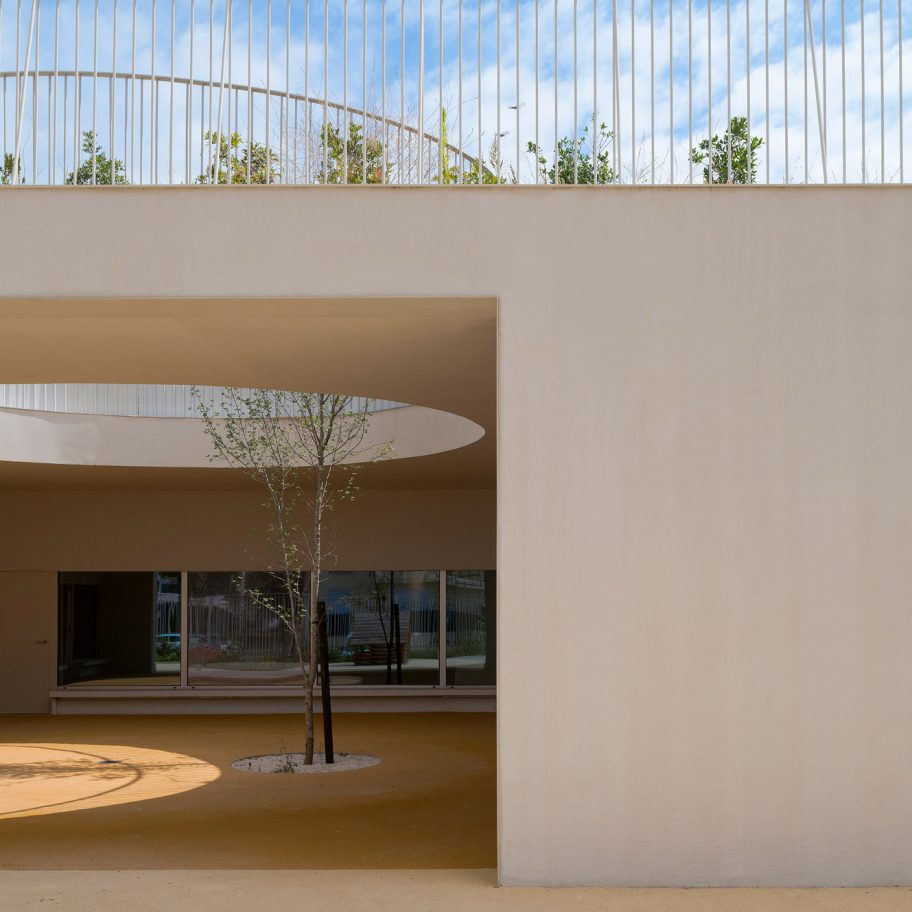 Circular holes connect playgrounds on two levels of a Lisbon school