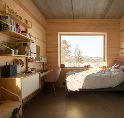 Bedroom with a desk in the red concrete house by Sanden+Hodnekvam