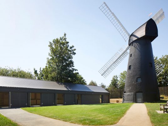 Black building next to black windmill with white sails