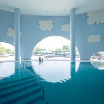 Blue indoor swimming pool with arches and clouds in children's hospital designed by Integrated Field