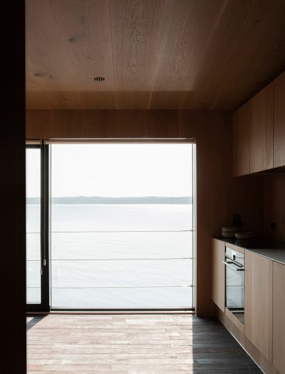 Kitchen of Fjord Boat House by Norm Architects has lake views
