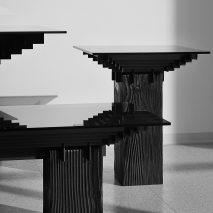 Gridded steel frames slice through charred-timber bases for Lin table series