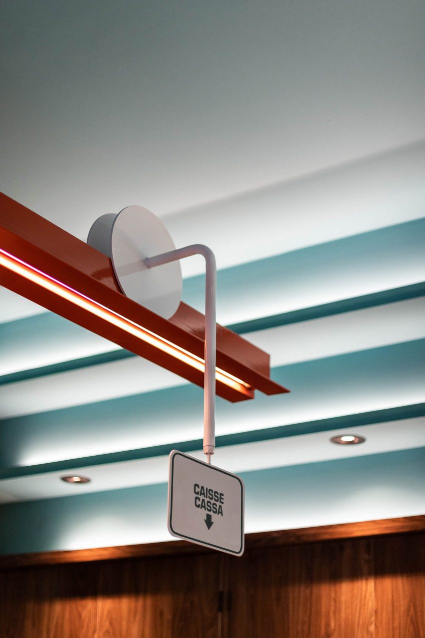 Italian signs illustrating where to pay and order slide along an orange painted steel beam above the bar