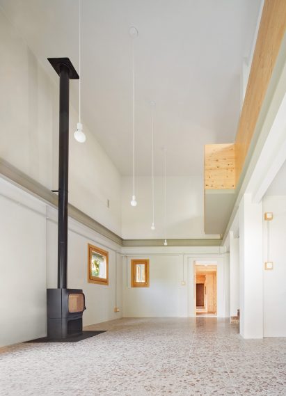 Pendant lighting fills the room and a wood burner sits a top the terrazzo floor
