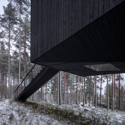 An elevated cabin with black-painted wood cladding