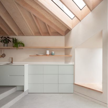A residential kitchen with an exposed timber ceiling and duck-egg blue cabinetry