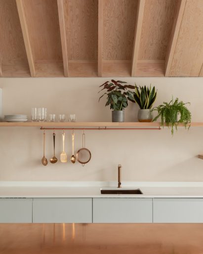 A pastel-hued kitchen with an exposed timber ceiling