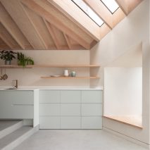 A residential kitchen with an exposed timber ceiling and duck-egg blue cabinetry