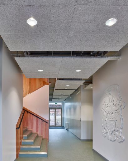 White walls with school crest next to timber lined stairwell