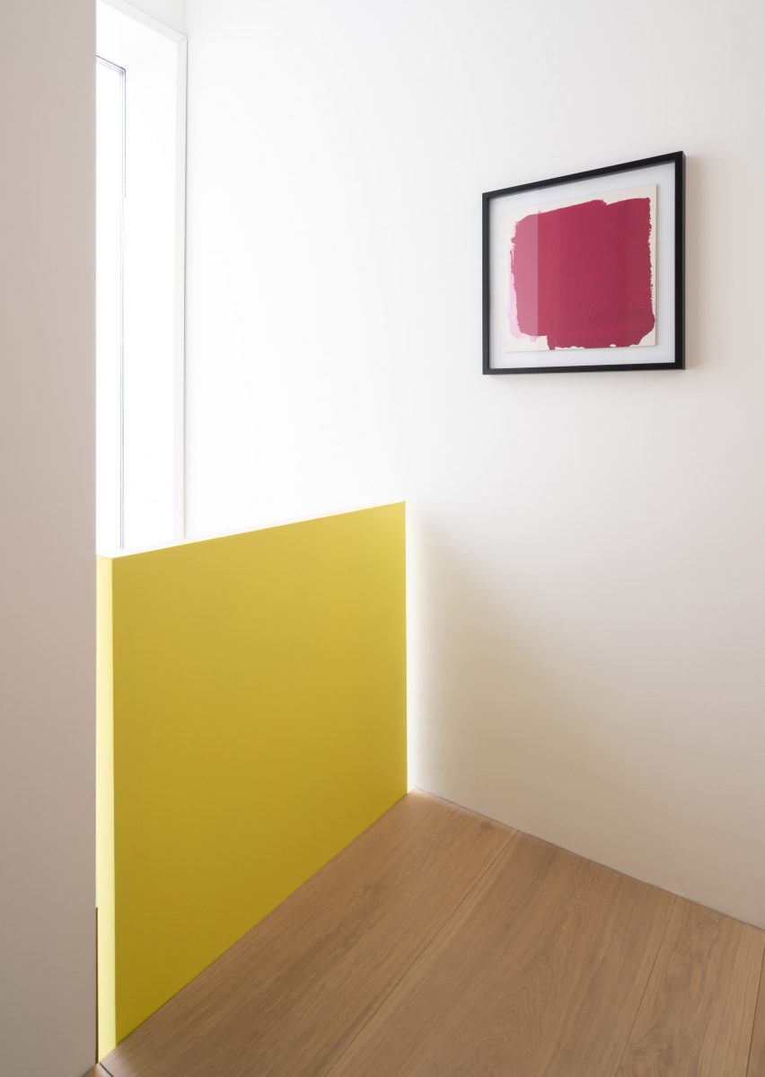 Yellow balustrade contrasts against wood floor and white walls
