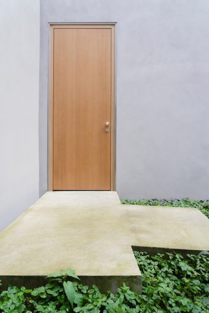 A wooden door is flush against the exterior walls by Batek Architekten