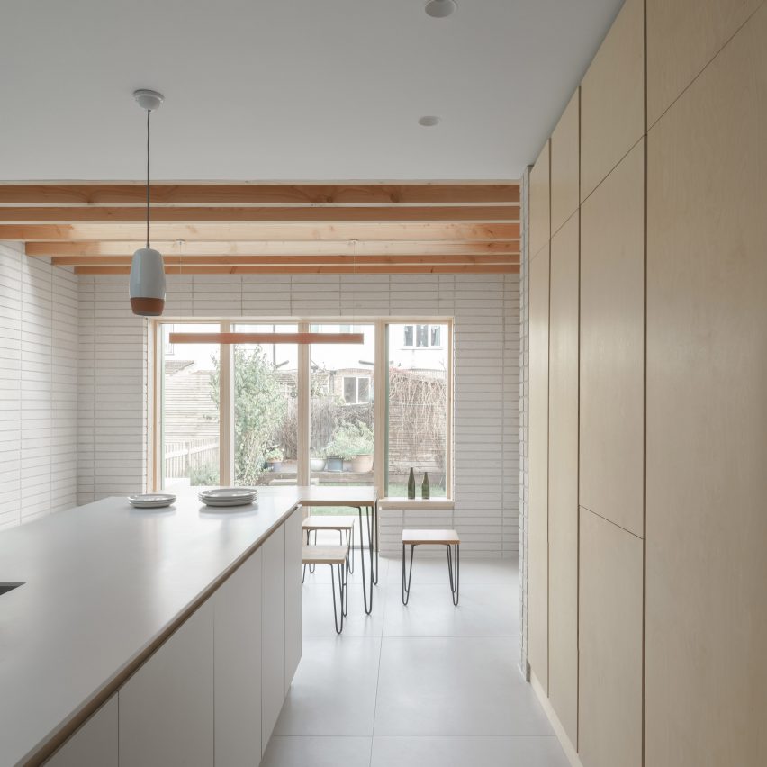 A white and wood-lined kitchen in a London house extension by DeDraft