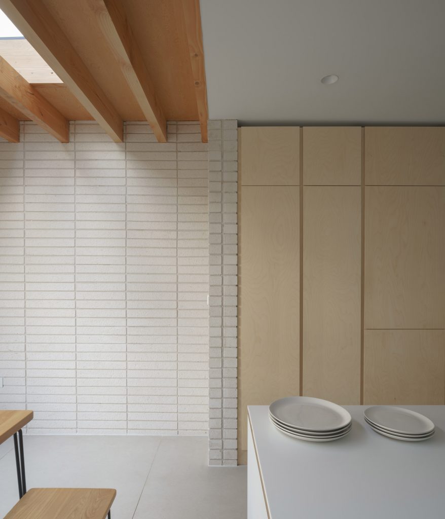 A white and wood-lined kitchen in a house extension in London by DeDraft