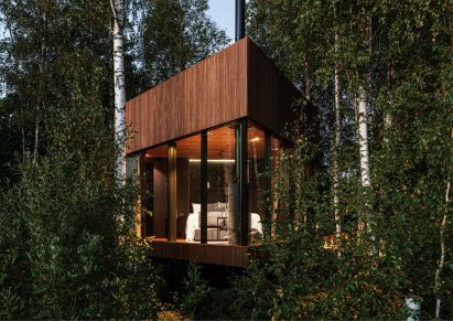 A glass and wood cabin in woodland
