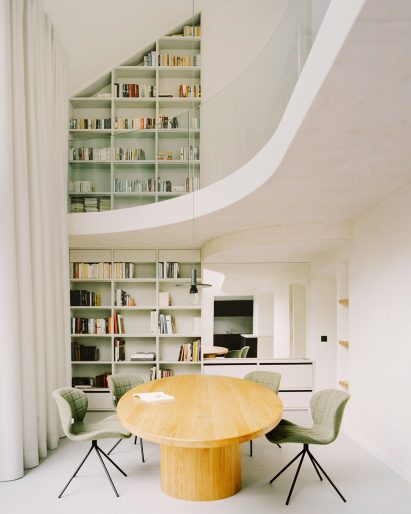 A white-walled double-height dining room in a Parisian townhouse