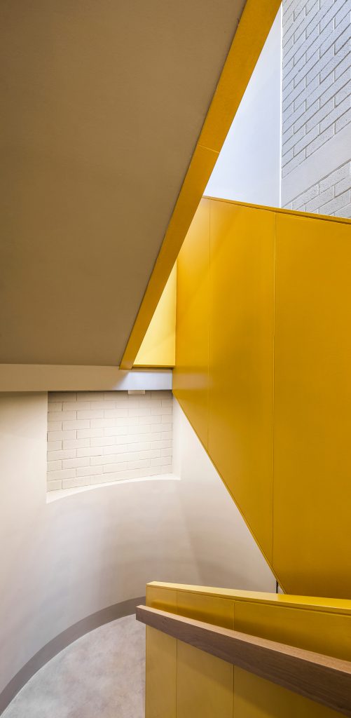 A yellow staircase contrasts against white walls