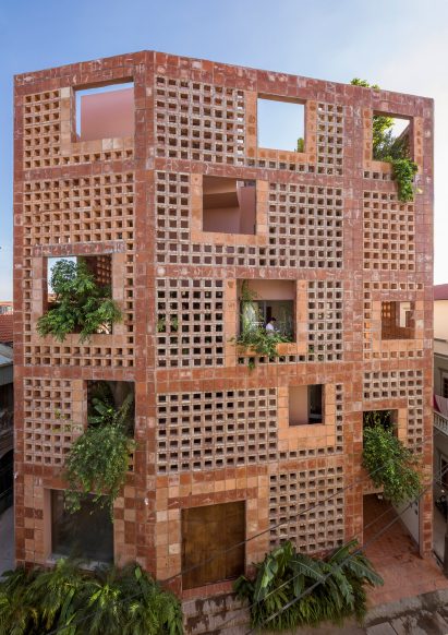 Green spaces are framed through openings in the ceramic facade by Vo Trong Nghia Architects