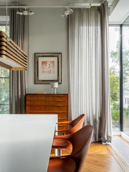 Dining room with orange chairs and brass pendant light in Moscow apartment by Blockstudio