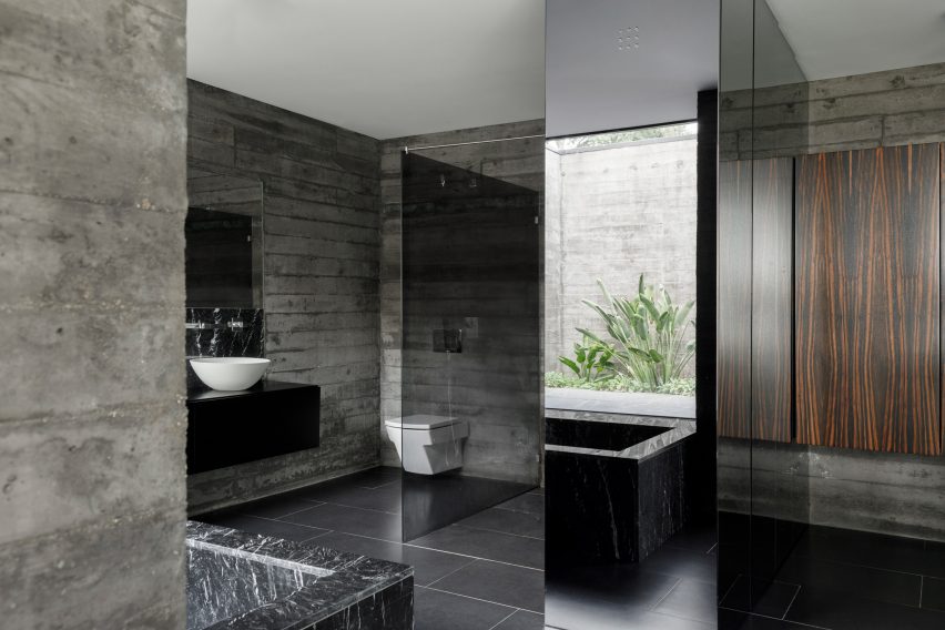 A concrete bathroom with black floor tiles
