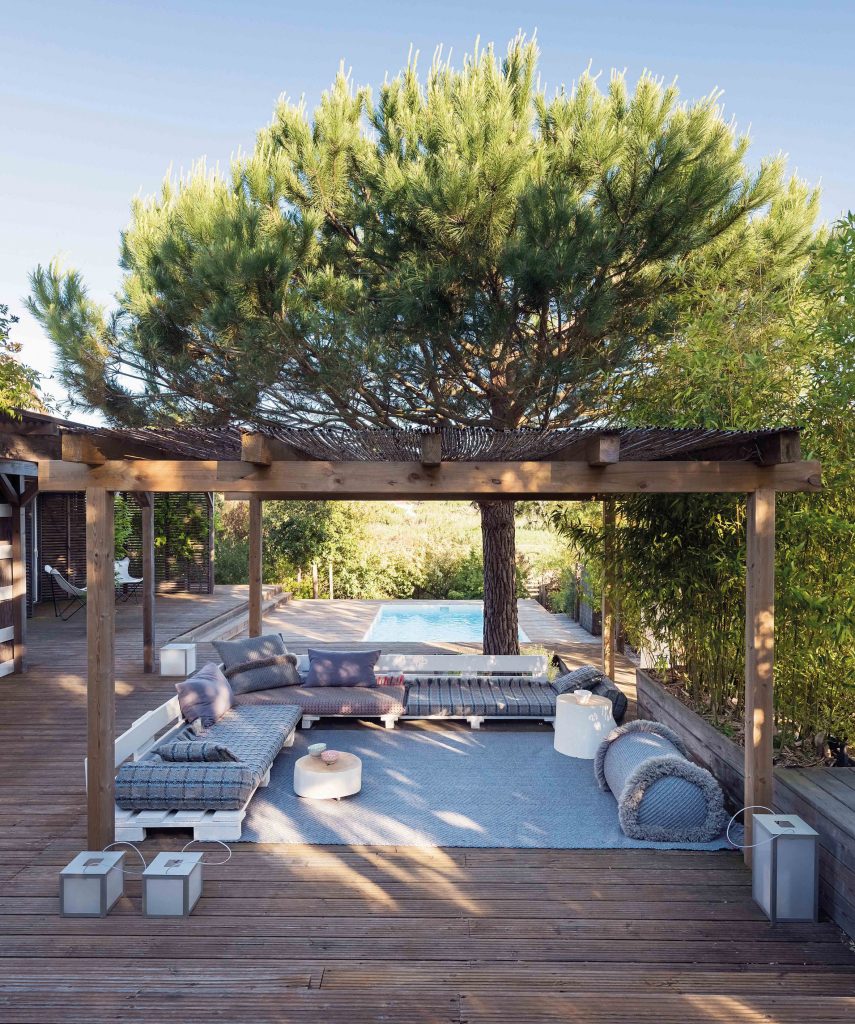 Blue outdoor furniture under a pergola by Patricia Urquiola