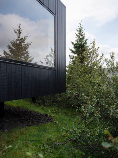 A facade with a large window and blackened-wood cladding