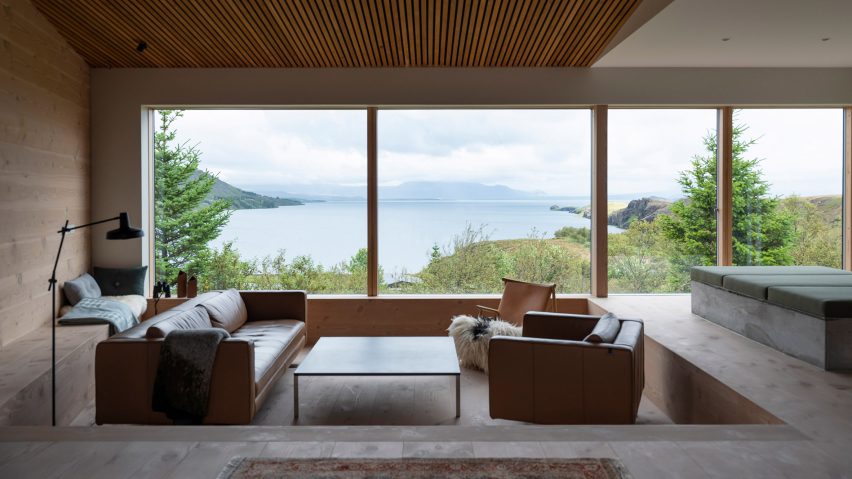 A sunken lounge with large windows framing a lake