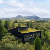 A black house with a green roof in rural Iceland