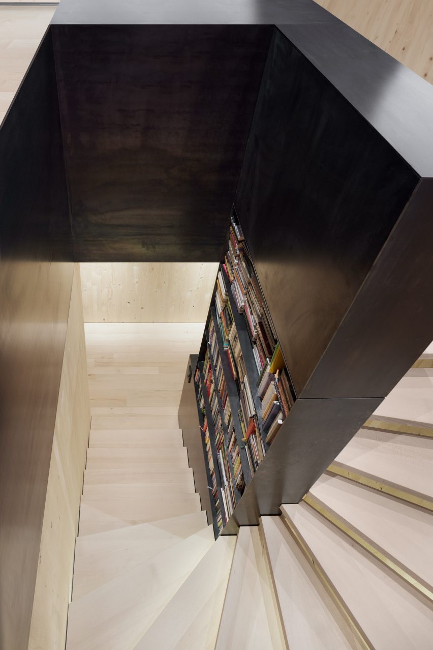 A spruce staircase with a black-steel bookcase