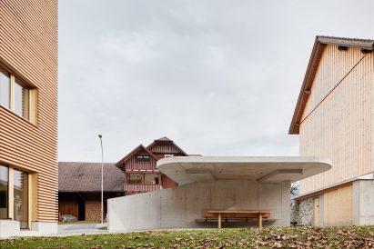 A concrete carport outside a timber-clad house