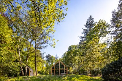 A wooden cabin with glazed walls in a forest opening