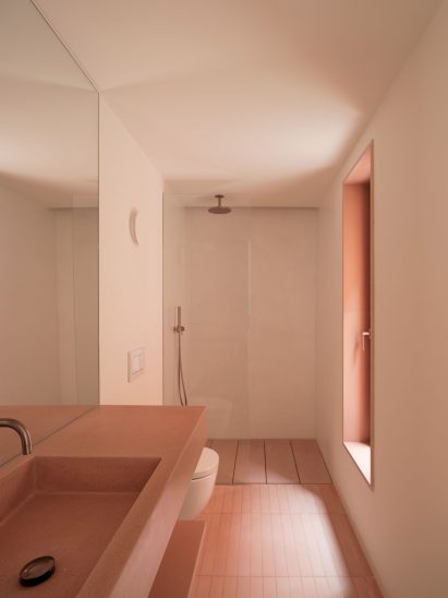 A pink-hued bathroom with a concrete sink