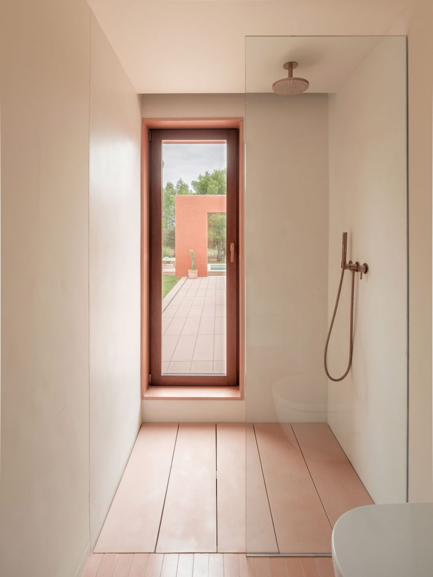 A white-walled shower with a pink concrete floor