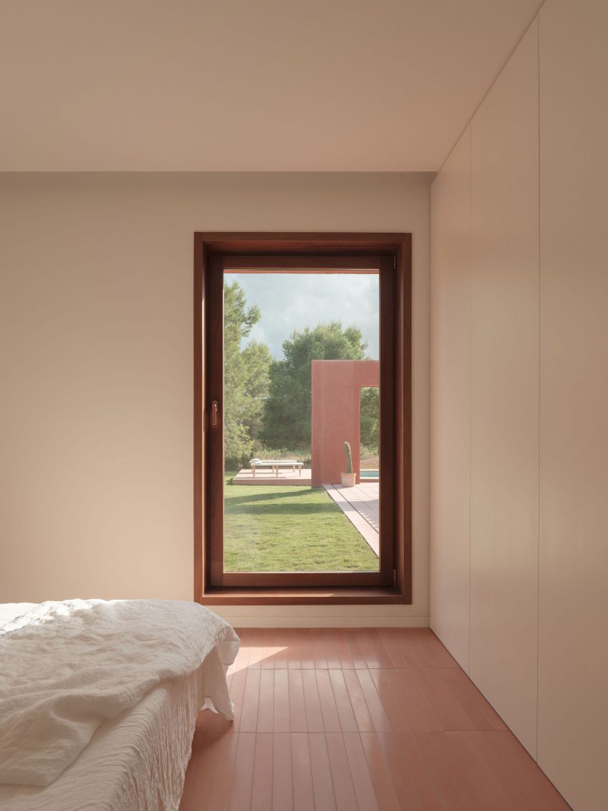 A bedroom with white walls and pink floor tiles