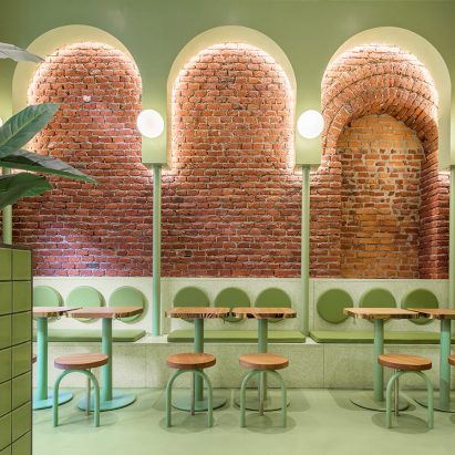 Green arches and exposed brick in seating area of Bun restaurant by Masquespacio