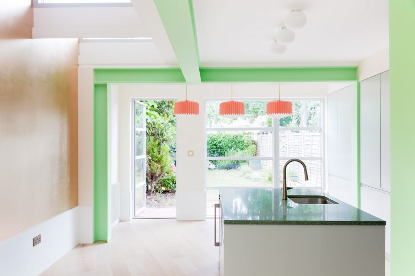 A bright white kitchen with green structural beams