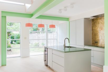 A white-walled kitchen with green-painted structural beams