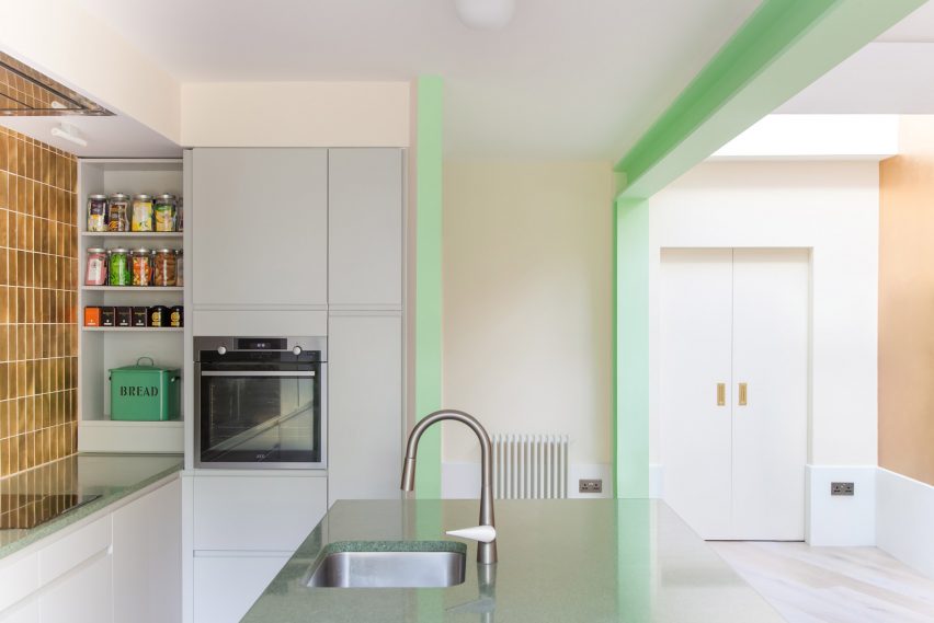 A white kitchen with green structural beams