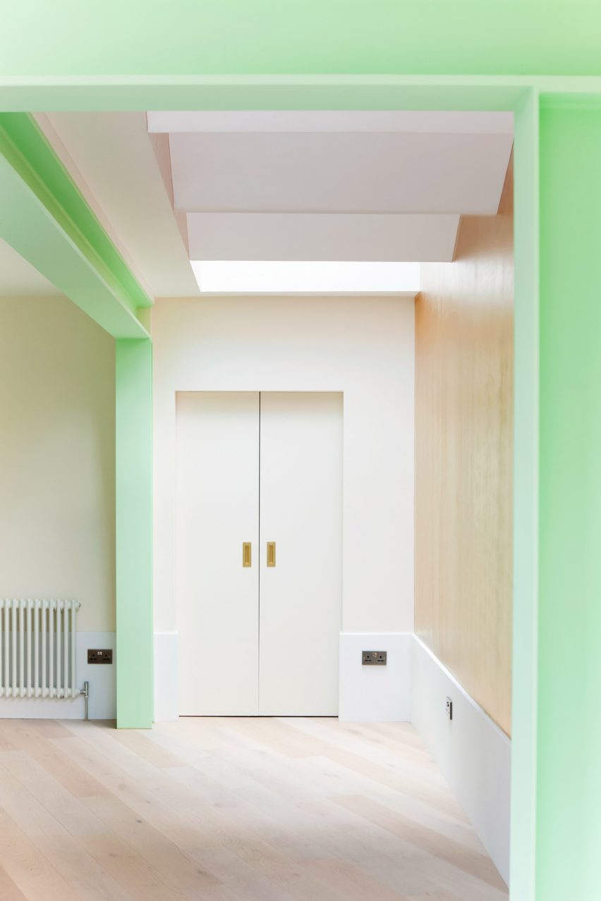 A white kitchen with green structural beams and a wooden floor