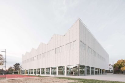 Glazed ground level exposes trusses by Wulf Architekten