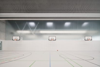 Basketball hoops are organised against a partially glazed wall
