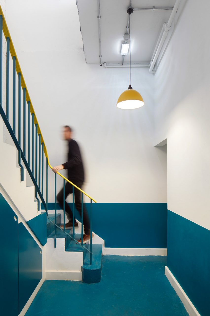A teal-hued staircase with a yellow banister