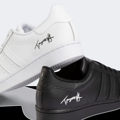 Mismatched Adidas Superstar trainers with engraved signature
