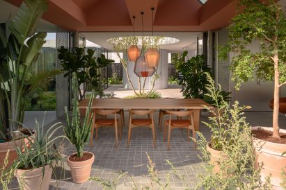Wooden table and chairs on tiled floor surrounded by flower pots