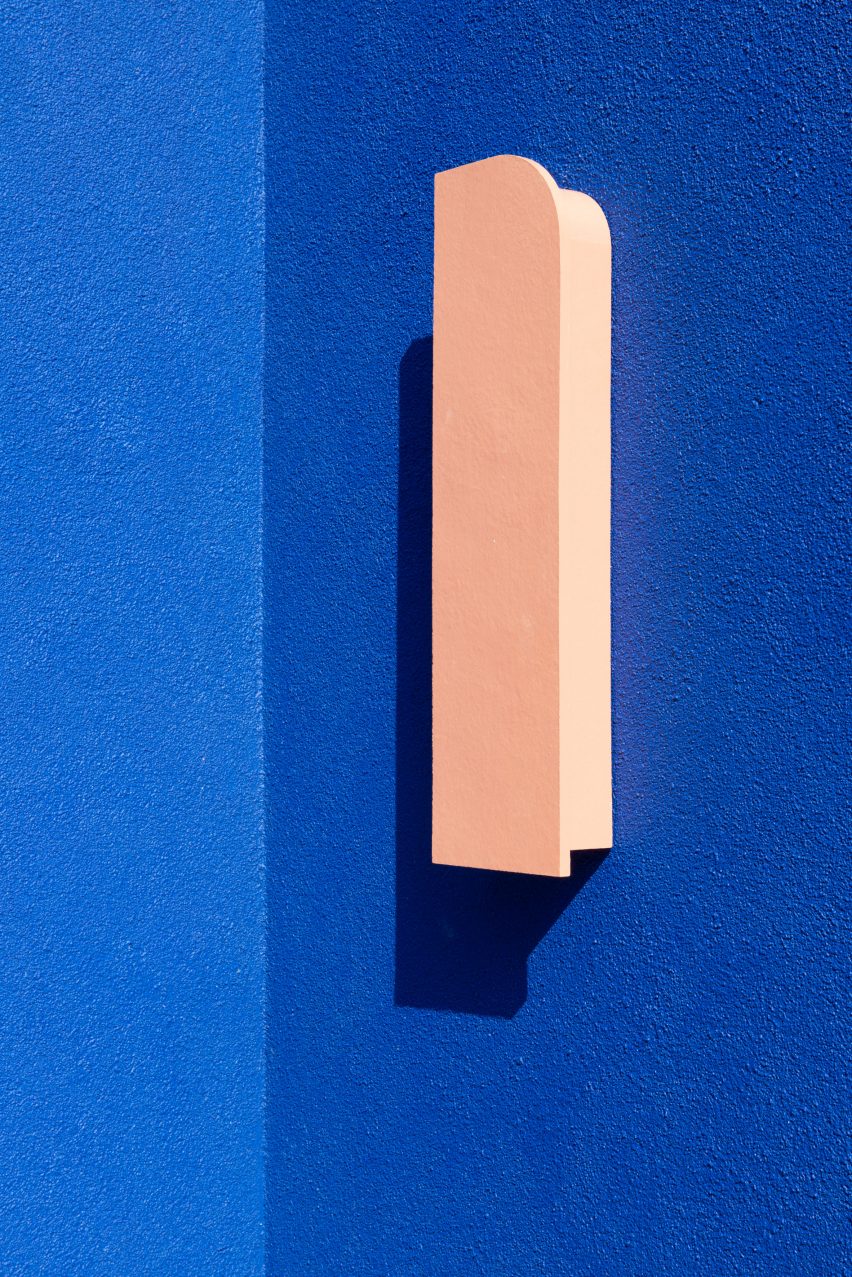 A bright blue wall and pink outdoor light
