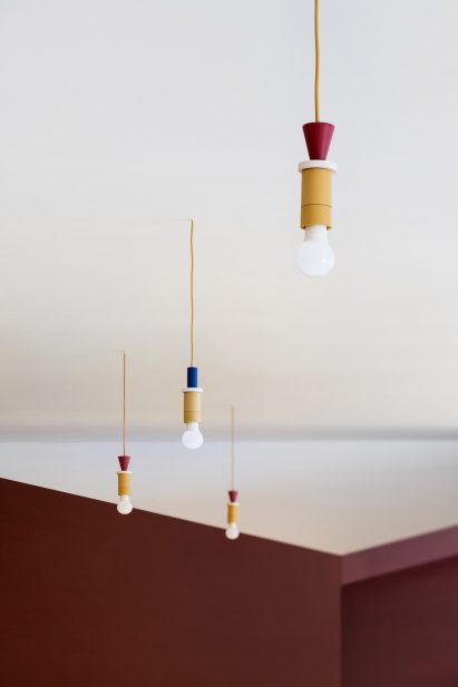 Pendant lights in mustard yellow, oxblood red and navy blue in Prague kindergarten by No Architects