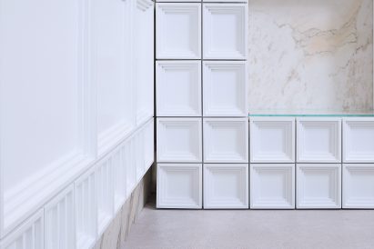 White MFF blocks form storage wall in tea shop by Raams Architecture Studio