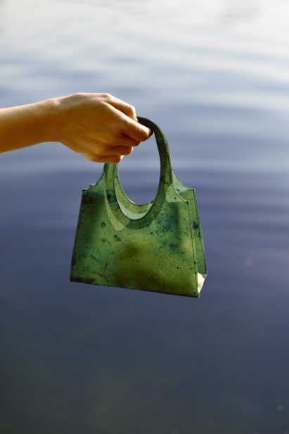 Green Sonnet155 carrier bag being dangled over water
